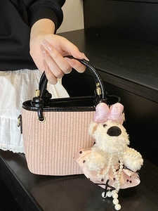 Pink woven straw handbag with black handles and cute teddy bear plush charm detail