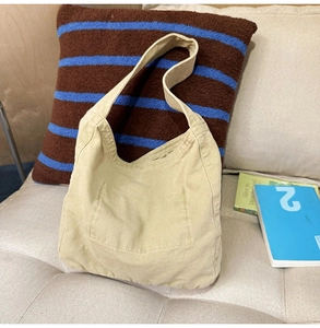Detail of cream canvas tote bag showing washed fabric texture and front patch pocket