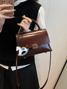 Deep brown glossy leather tote bag with a rocking horse charm and top handle