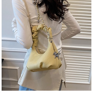 Détail du sac à main jaune en cuir litchi avec poignée froncée et pendentif cheval argenté