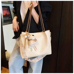 Detail of off-white tote bag with litchi grain texture and plush lamb charm accessory