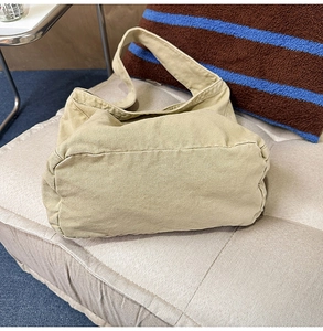 Detail of durable khaki canvas tote bag with wide shoulder strap on quilted texture