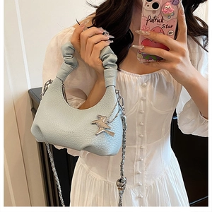 Détail du sac croissant bleu clair avec poignée froncée et pendentif oiseau en argent