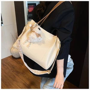 Detail of beige faux leather tote bag with bohemian woven strap and cute plush lamb charm