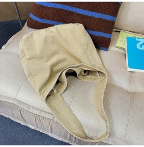 Detail of khaki washed canvas tote bag with wide strap on sofa for casual use