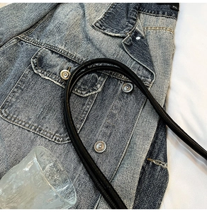 Détail d'une veste en jean délavé bleu avec coutures blanches et étiquette XL
