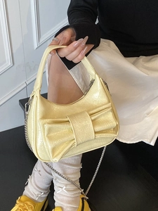 Bright yellow bow bucket bag in glossy patent leather with a detachable silver chain strap