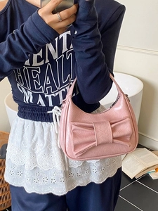 Pink bow-knot saddle handbag with glossy finish shown in a stylish mirror selfie