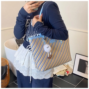 Blue and yellow striped woven tote bag with light blue leather straps and plush charm