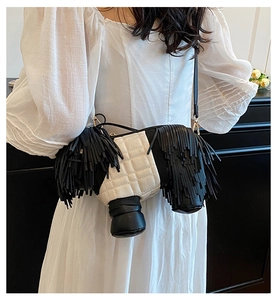 Detailed view of dog-shaped crossbody bag with long black fringe and quilted leather