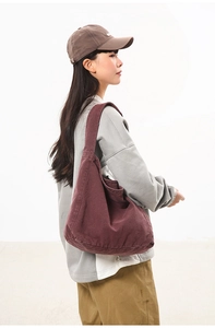 Side view of a large capacity dark red canvas crossbody bag on a female model