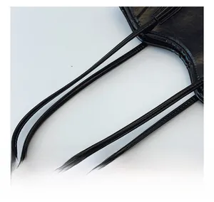 Detailed close-up of slim black leather handles with fine stitching on a tote bag