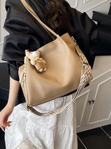Large khaki tote bag with a geometric pattern strap and a cute bear charm accessory