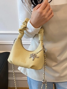 Sac à main en cuir jaune pâle avec poignée plissée et breloque cheval sur fond blanc