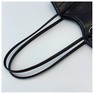 Detail of black leather tote bag showing double shoulder straps and silver metal buckles