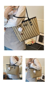 Detail of striped woven tote bag featuring black leather handles and plush charm accessory
