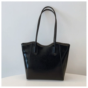 Front view of a black glossy patent leather tote bag with long slim shoulder straps