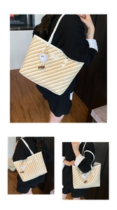 Detail of yellow and white striped tote bag with a white shoulder strap and plush charm