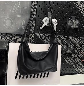 Detail of minimalist black PU leather crescent hobo bag in urban industrial setting
