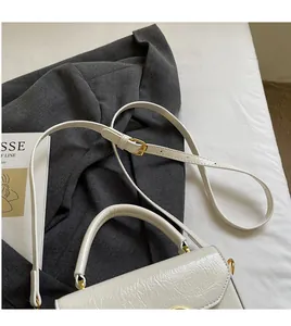 Gros plan du sac à main en cuir froissé crème avec boucles dorées élégantes