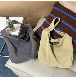 Detail of grey and khaki large canvas tote bags with wide shoulder straps on a sofa