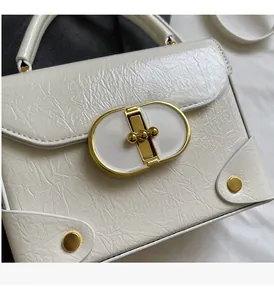 Détail du cuir verni blanc plissé avec fermoir rotatif ovale doré sur un petit sac à main
