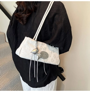 Détail d'un sac sous les bras blanc avec texture florale 3D et pendentif nœud argenté