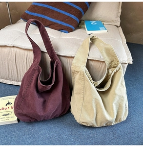 Detail of large canvas tote bags in plum and khaki colors shown on a beige sofa