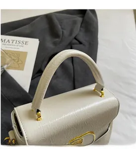 Détail du sac en cuir plissé blanc avec finitions dorées et poignée fixe robuste