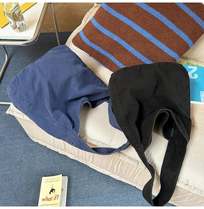 Detail of navy and black canvas tote bags on a sofa showing thick cotton fabric texture