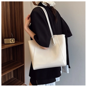 Close-up of a cream white leather tote bag with long handles against a vintage background