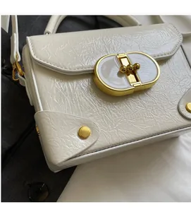 Détail du sac à main en cuir verni plissé crème avec fermoir rotatif ovale en métal doré