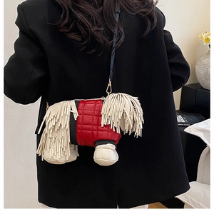 Detail of creative sheepdog crossbody bag with beige tassels and red quilted leather