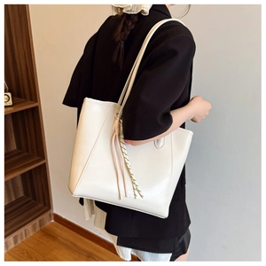 Close-up of beige tote bag with fine leather texture and colorful rope charm accessory