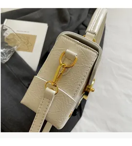Détail du fermoir en métal doré sur un sac à main blanc à texture crocodile chic
