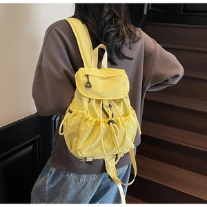 Macro detail of bright yellow nylon drawstring backpack with side pockets and flap closure