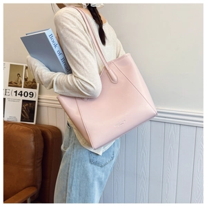 Model wearing large light pink PU leather tote bag with long shoulder strap for commuting