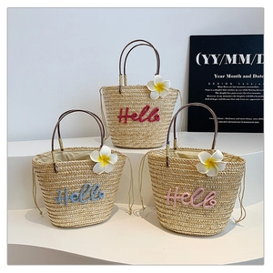 Detail of straw bucket bags with Hello embroidery in red, blue, and pink colors