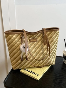 Large striped woven tote bag with brown leather handles and a plush doll pendant