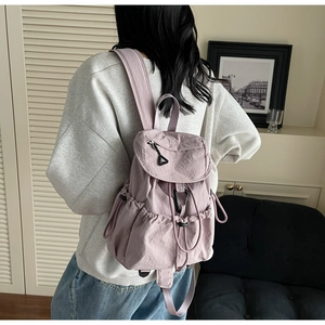 Detail of lavender nylon backpack with drawstring closure and ruched texture in home setting