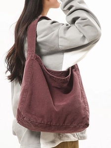 Large burgundy canvas hobo tote bag worn by model with minimalist shoulder strap design