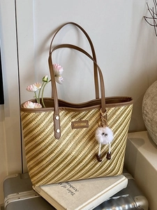 Large striped tote bag with leather handles and monster charm on a suitcase
