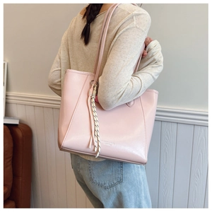 Detail of light pink large tote bag with woven charm and fashion logo for daily commute