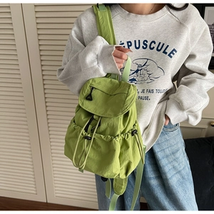 Detail of green nylon drawstring backpack featuring flap closure and side pockets