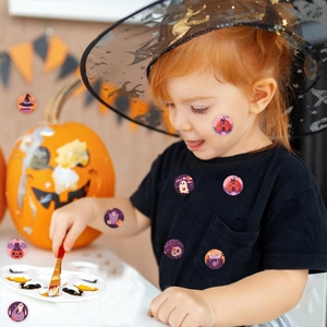 Child wearing cartoon Halloween stickers on face and shirt with pumpkin backdrop