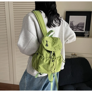 Detail of green nylon drawstring backpack with flap closure and adjustable side pockets
