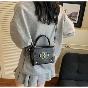 Détail d'un mini sac noir embossé avec boucle dorée et bandoulière chaîne sur modèle
