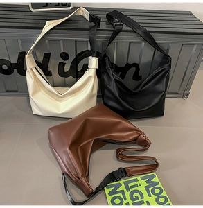 Detailed view of large crescent tote bags in white, black and brown leather materials