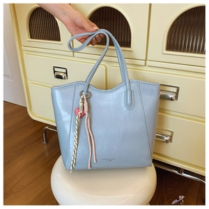 Detail showing the light blue PU leather tote bag with a pink heart charm and hand-held strap