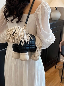 Quilted sheepdog crossbody bag with cream tassels worn by a model in home setting